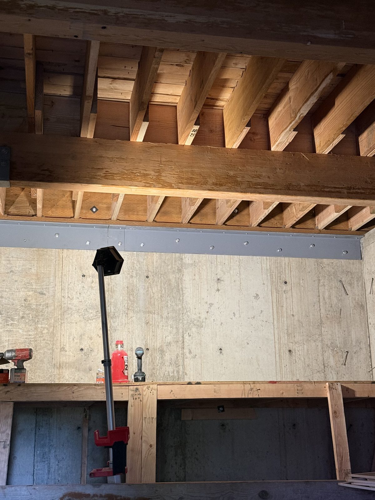 Completed structural dry rot repair — steel beam carrying new floor framing under an existing garage